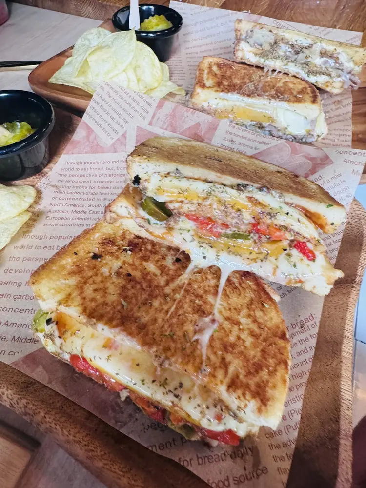 Split toastie with a long cheese pull on newspaper wrap